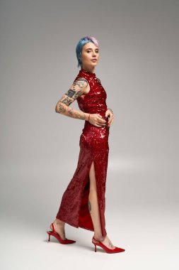 Güzel genç bir kadın zarif bir şekilde kırmızı elbiseyle poz veriyor. Şen şakrak kış atmosferleri sergiliyor..