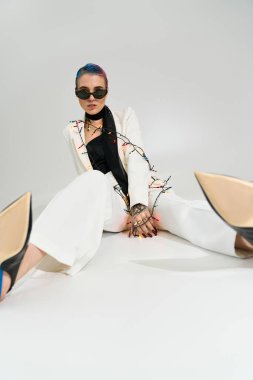 Şık bakışlı genç bir kadın neşeli ışıkların arasında oturuyor, canlı bir kış ruhunu sergiliyor..