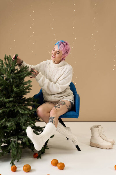 Радостная молодая женщина добавляет украшения к рождественской елке, наслаждаясь зимним духом.