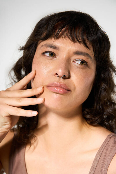 Young woman engages with the camera, showcasing her trendy outfit and natural beauty.