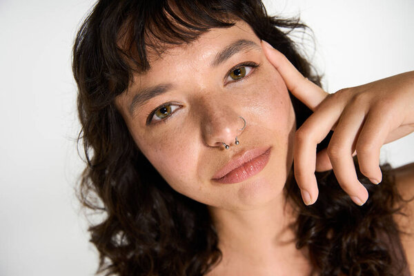 Молодая женщина с вьющимися волосами уверенно позирует, подчеркивая ее чувство стиля и обаяние.