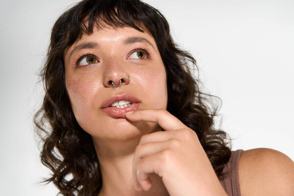 Молодая красивая женщина в модной одежде вдумчиво смотрит, олицетворяя современную элегантность и стиль.