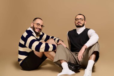 Şık giyinmiş iki kardeş, yumuşak bir yüzeyde birlikte otururlar. Çekicilik ve tarz yayarlar..