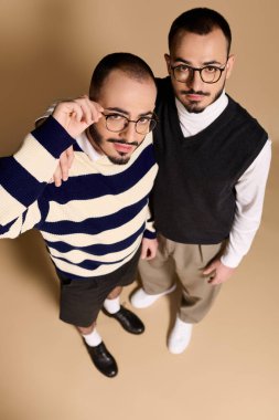 İki yakışıklı ikiz kardeş, tarafsız bir arkaplanda şık bir şekilde poz veriyorlar..