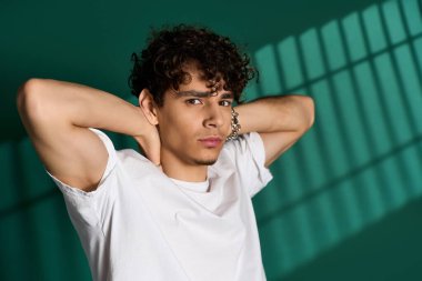 Kıvırcık saçlı şık bir adam şık kıyafetlerini canlı bir stüdyoda gösteriyor..