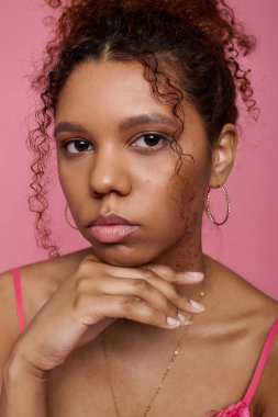 Güzel genç bir kadın zarif bir şekilde poz veriyor, şık kıyafetlerini ve ışıl ışıl özelliklerini vurguluyor..