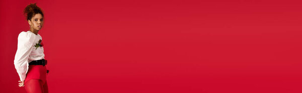 Молодая женщина выставляет напоказ шикарный костюм на ярком красном фоне.