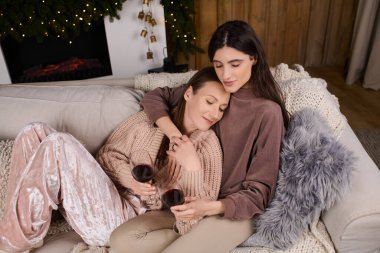 Samimi giyinmiş iki güzel kadın, kış boyunca şöminenin yanında hassas anlar paylaşırlar..