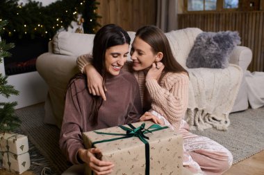 Neşeli kış şenliklerinde iki kadın samimi kıyafetler içinde kahkahalar ve hediyeleri paylaşıyor..