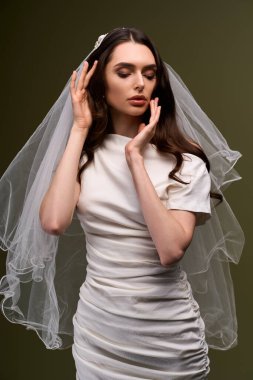 Güzel bir gelin şık elbisesi ve zarif duvağıyla sessiz bir anın tadını çıkarır..