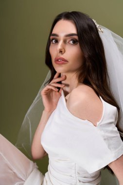Genç ve güzel gelin zarif bir yüz ifadesiyle zarifçe poz veriyor, zarafetini ve cazibesini sergiliyor..