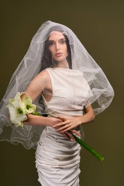 Güzel, genç bir gelin, elinde buket, göz kamaştırıcı bir elbise içinde mutluluk saçar..