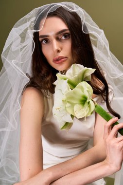 Güzel gelin, narin bir duvak takıyor, çarpıcı bir buket tutuyor, neşe ve zarafet saçıyor..