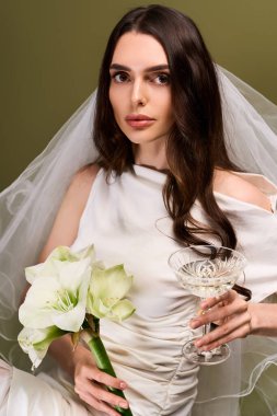 Uzun saçlı genç bir gelin güzel bir buket ve kristal bir bardak tutuyor, mutluluk saçıyor..