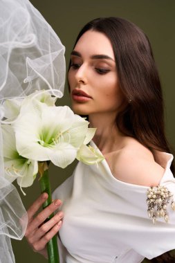 Genç bir gelin zarif buketine hayran kalır, zarif duvağıyla çevrili, mutlu anları yakalar..