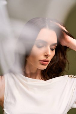 Güzel genç bir gelin, yumuşak ışığın rüya gibi atmosferiyle çevrili saçlarını nazikçe düzeltir..