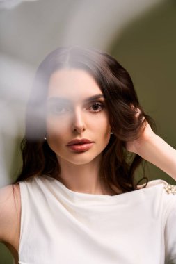 Mutlulukla dolu genç bir gelin, eli saçlarında zarifçe poz verir, zarafet saçar..