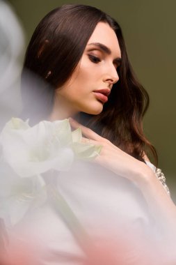 Güzel, genç bir gelin zarif poz verir, yumuşak çiçeklerle çevrili, saf mutluluk ve neşeyi yakalar..