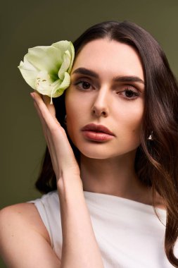 Genç bir gelin, zarif bir çiçeğe hayran kalır. Huzurlu bir ortamda zarafet ve güzelliği simgeler..