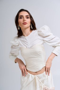 Genç gelin zarifçe poz veriyor, zarif tarzını sergiliyor ve huzurlu ortamda neşe saçıyor..