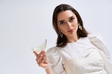 Büyüleyici genç bir gelin, büyük gününde neşe ve zarafet saçarken narin bir bardak tutar..