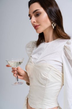 Güzel gelin elinde köpüklü bir içki tutuyor, şık gelinliğiyle mutluluk saçıyor..