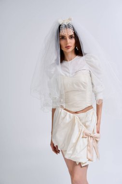 Güzel bir gelin kendine güvenerek poz verir. Huzurlu bir ortamda eşsiz bir gelinlik sergiler..