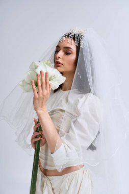 Genç gelin elinde bir buket tutarken neşe saçıyor, baş döndürücü bir gelinlik içinde..