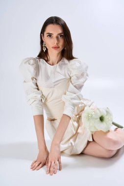 Güzel gelinlik ve çiçeklerle süslenip zarif bir şekilde poz verirken güzel gelin mutluluk saçar..