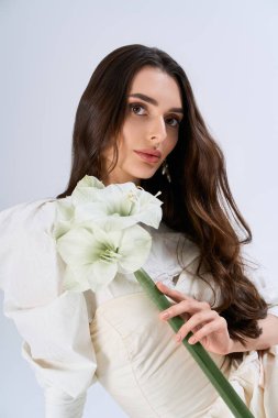 Güzel, genç bir gelin, elinde çiçek aranjmanıyla zarafetini ve cazibesini sergiliyor..