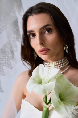 Çekici bir gelin uzun saçlarıyla çiçekleri tutar, rüya gibi bir ortamda sevgi ve mutluluk saçar..