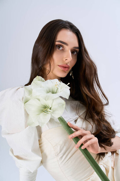 Красивая молодая невеста демонстрирует свою элегантность и очарование, держа безмятежный цветок расположение.