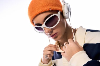 Modayı takip eden bir genç, beyaz bir arkaplana karşı güvenle poz verir..