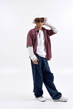 Modayı takip eden bir genç, kareli gömlek, panama şapkası ve güneş gözlüğü takar..