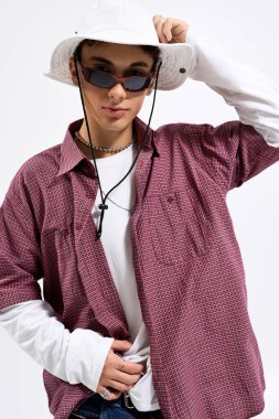 Şık bir genç, kareli gömlek, uzun kollu ve güneş gözlüklü birine güven yayar..