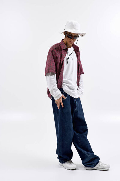 Стильный подросток уверенно позирует в клетчатой рубашке и панамской шляпе, воплощая моду Gen Z.