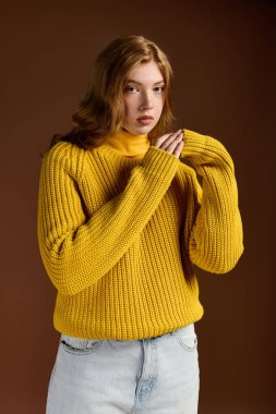 Genç kızıl saçlı bir kadın, güzel poz verirken kışlık süveterini giyer..