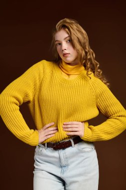 Kendine güvenen genç bir kızıl rahat bir kış süveteri içinde poz veriyor, mevsimlik tarzını sergiliyor.