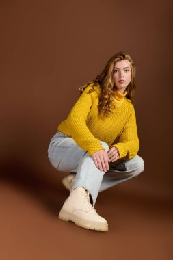 Genç bir kızıl, sıcak bir kazak ve şık çizmelerle rahatça poz verir..