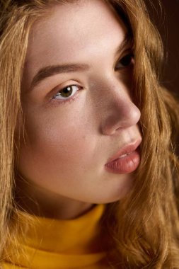 Kışlık süveter giyen güzel bir kızıl, kahverengi bir arka fona sıcaklık ve tarz saçıyor..