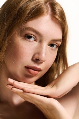 Genç, kızıl saçlı bir kadın makyajsız güzelliğini sergiliyor.