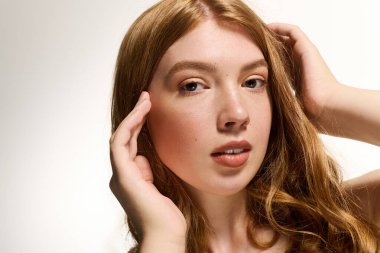 Bu büyüleyici kızıl saçlı kadın, sakin bir stüdyoda parlak cildini ve doğal makyajını ön plana çıkarıyor..