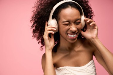 Neşeli genç bir kadın, en sevdiği müziği canlı pembe bir arka plana karşı seviyor..