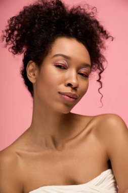 Kıvırcık saçlı genç bir kadın cesur bir makyaj ve kendine güvenen yaratıcı bir hava sergiler..