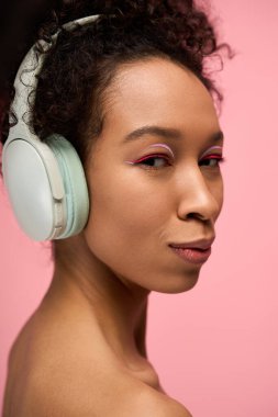 Geniş kulaklık takan, mutluluk ve huzur saçan genç bir kadının parlak portresi..
