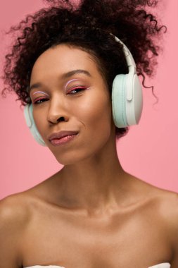 Güzel bir genç kadın kulaklıkla pembe bir arka plana gülümsüyor, seste kayboluyor..