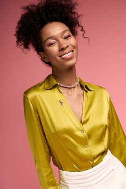 Parlak ve neşeli genç bir kadın sıcak bir şekilde gülümser. Renkli bir ortamda kendine güven ve tarz yayar..