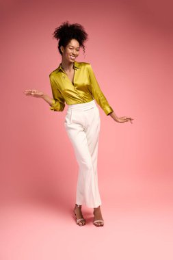 Kıvırcık saçlı güzel genç bir kadın şık bir elbise ve ışıl ışıl bir gülümsemeyle mutluluk saçar.