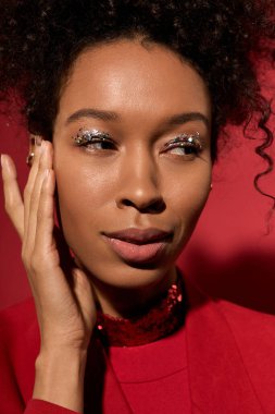 Kıvırcık saçlı kadın zarif pozlar veriyor. Parlak makyajını ve büyüleyici bakışlarını vurguluyor..