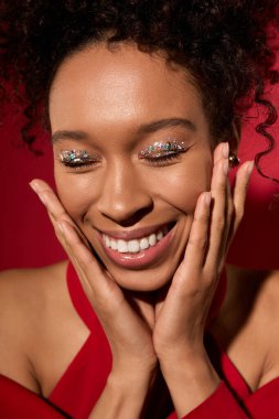 Neşeli genç kadın mutluluğunu ışıltılı bir gülümseme ve ışıltılı bir göz makyajı ile paylaşıyor..